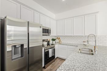 A kitchen with a granite countertop and stainless steel appliances.